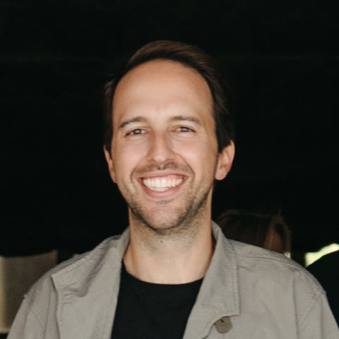 Matias smiling, in a grey jacket over a black t-shirt